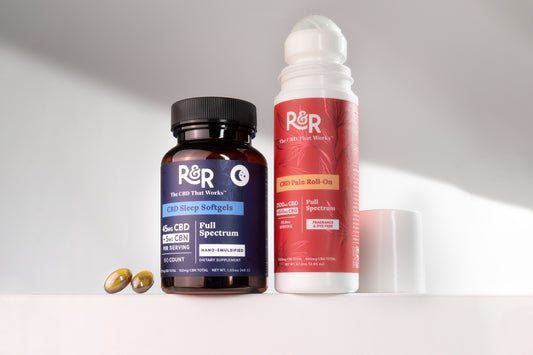 One R&R CBD sleep soft gel and one pain roll-on rest on a white surface