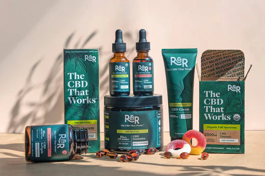 Some R&R products, such as CBD tinctures, CBD softgels, gummies, and creams, are placed on the floor, with some opened gummies and softgels scattered around