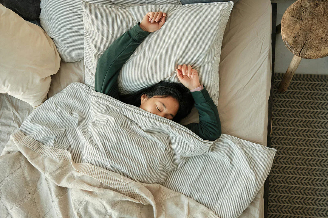 A lady is sleeping peacefully in bed, covering her body with a comforter