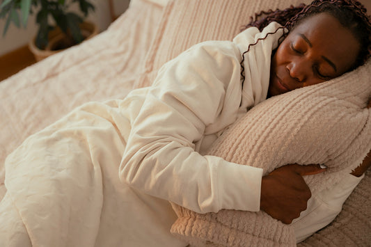 A woman sleeps peacefully, dressed warmly with her head resting on a soft pillow